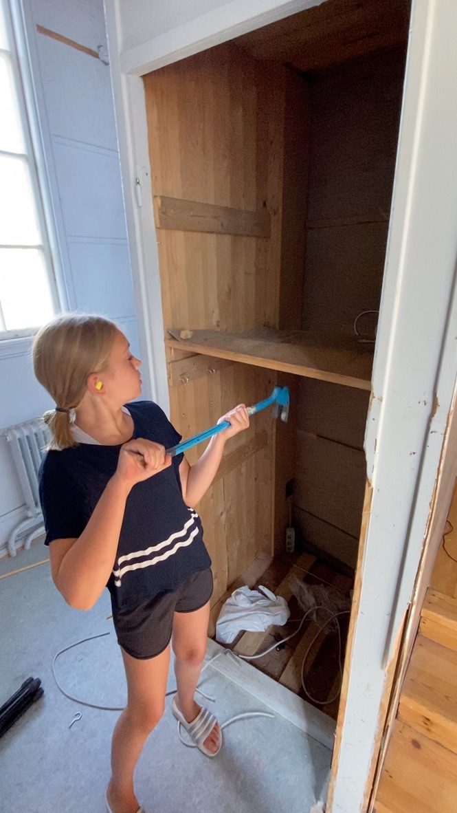 Flicka målar insidan av ett gammalt skåp med roller