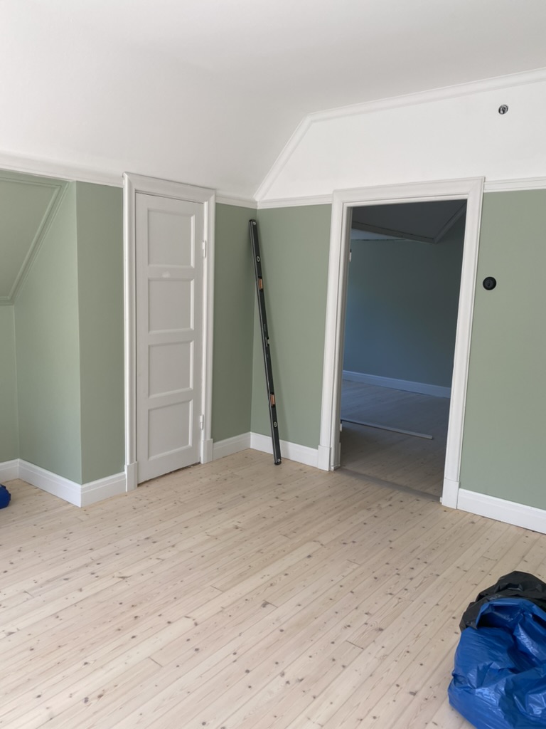 Rum med salviagrön vägg och furugolv, stege kvar