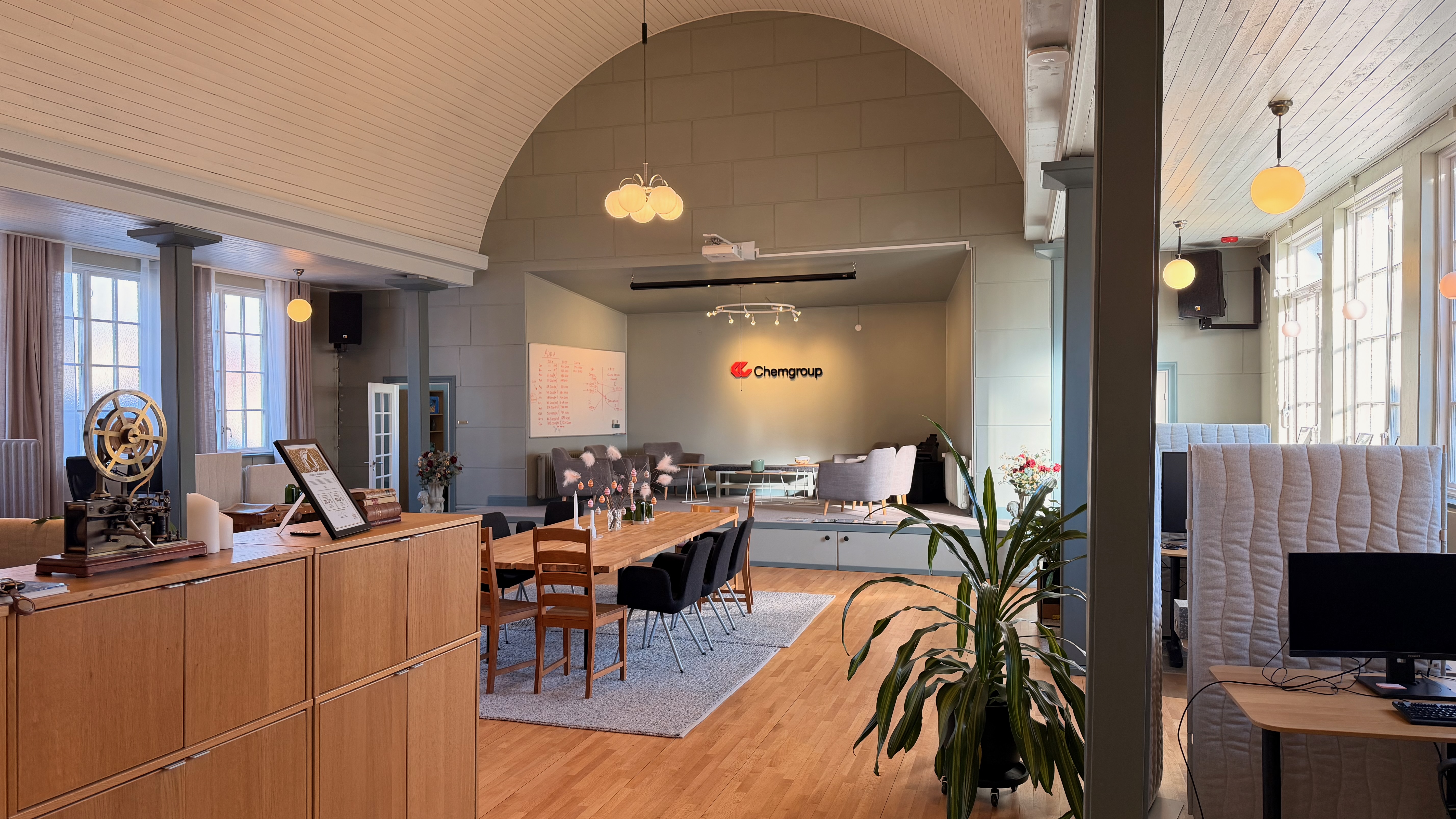 Översikt av stora salen med valvtak, matbord och Chemgroup-logotyp på scenen