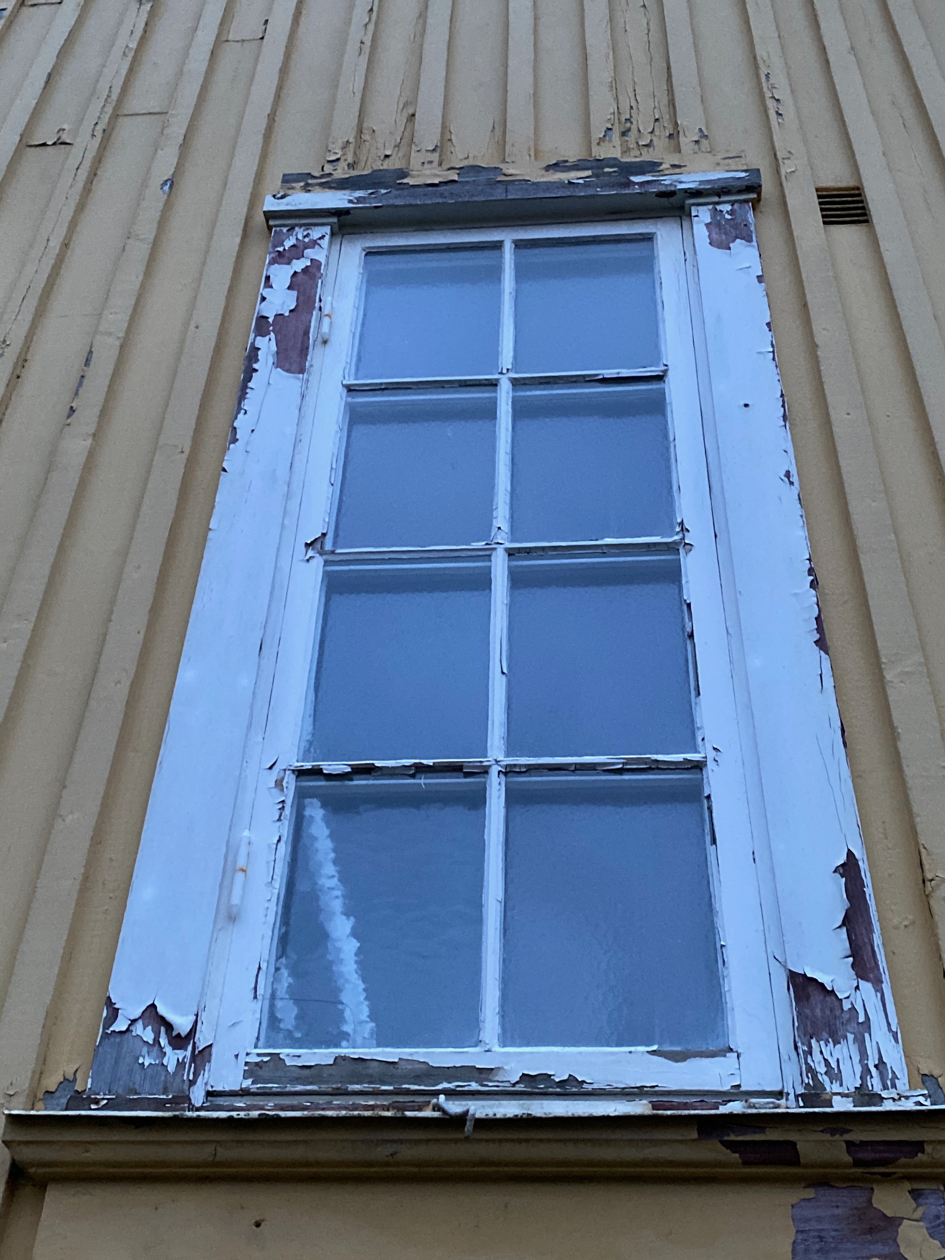 Fönster med kraftigt flagnad vit färg