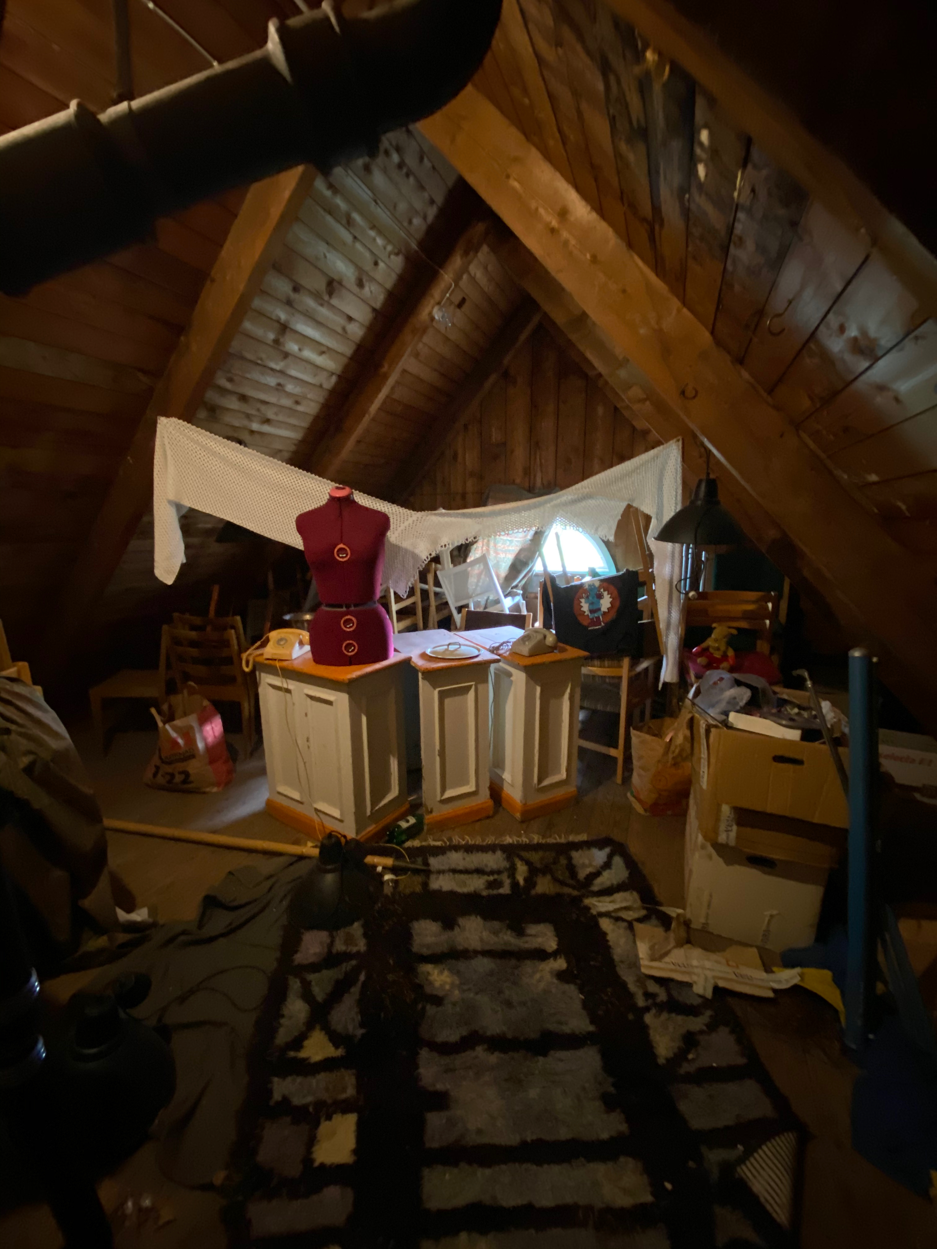 Mörkt vindsutrymme med provdocka och lakan