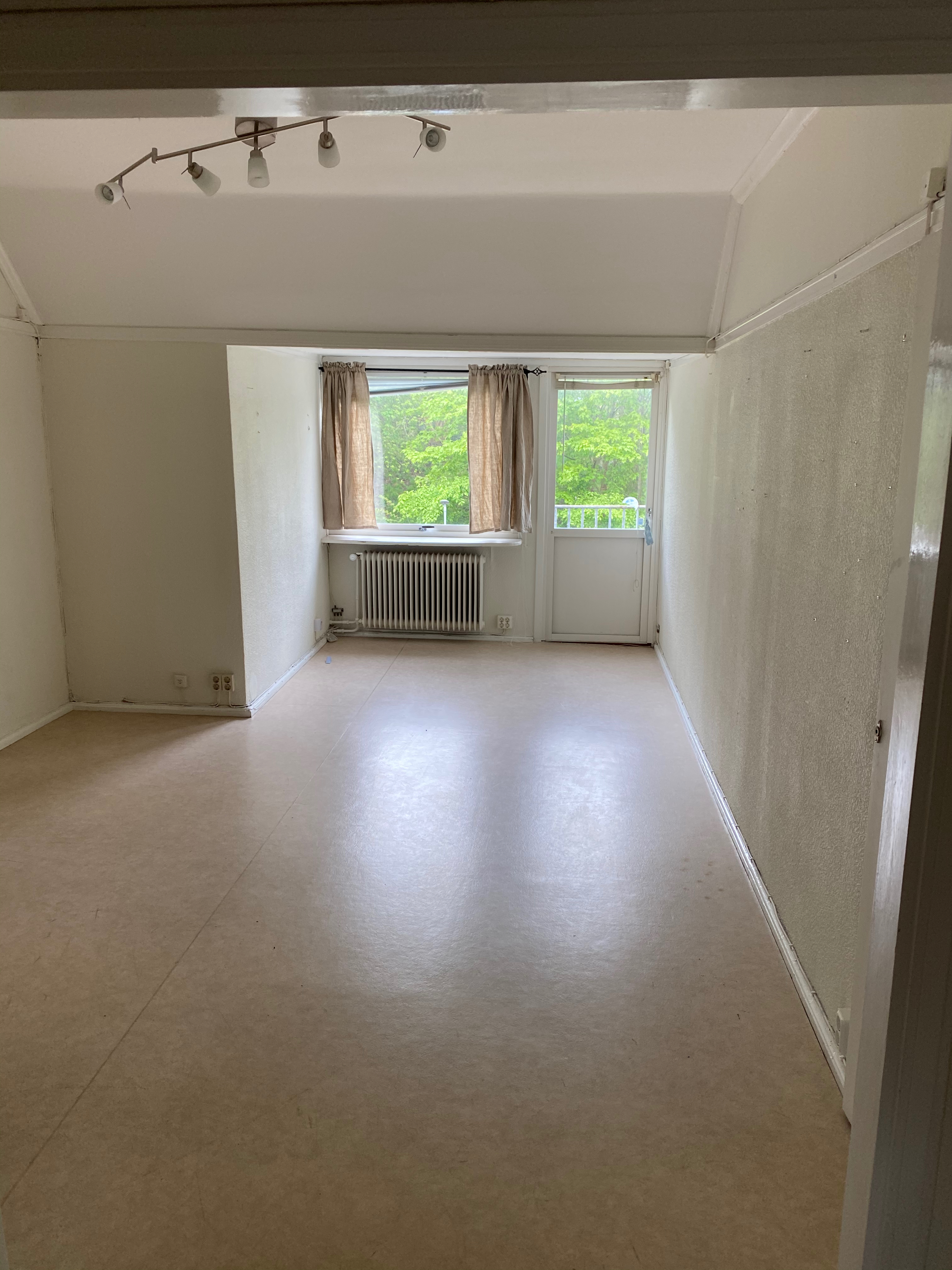 Tomt rum med linoleumgolv och gardiner
