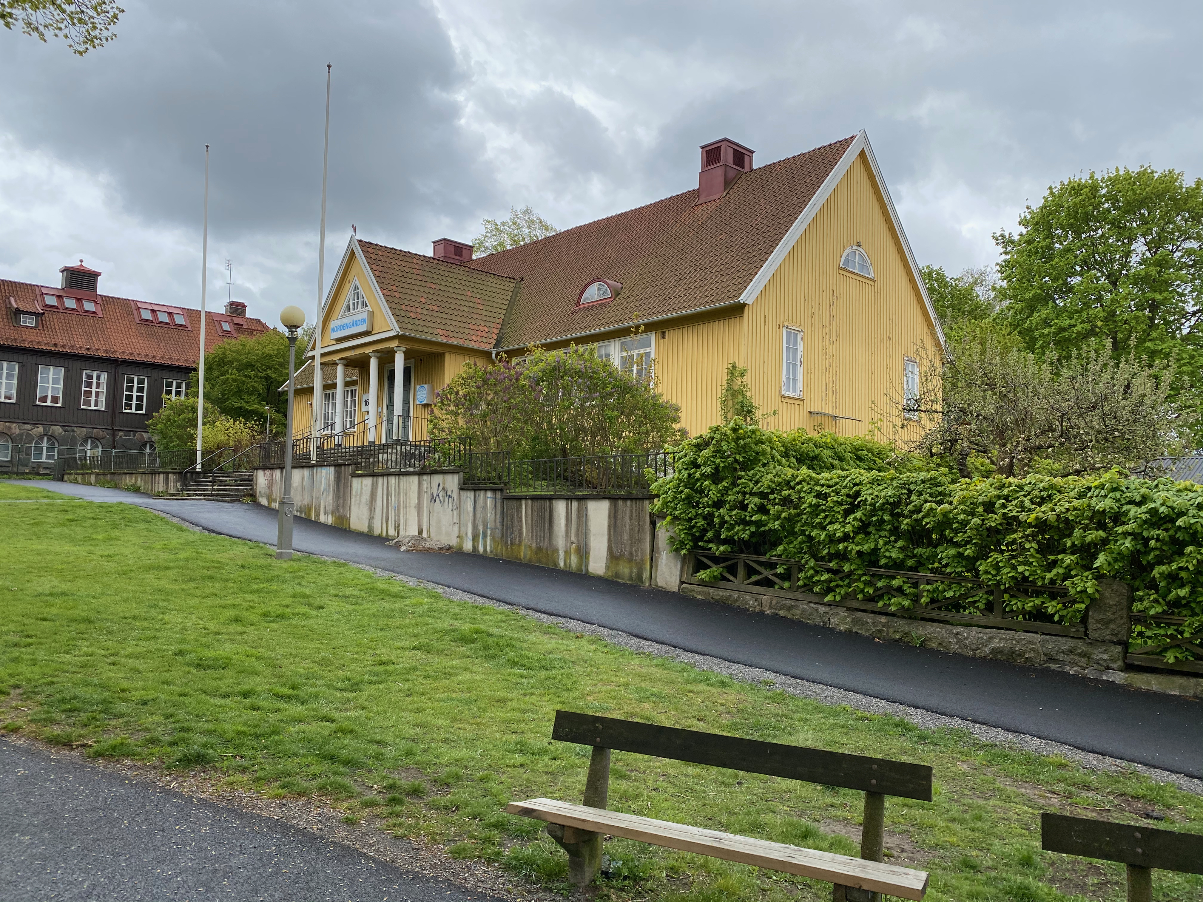 Villan sedd från vägen med häckar och flaggstång