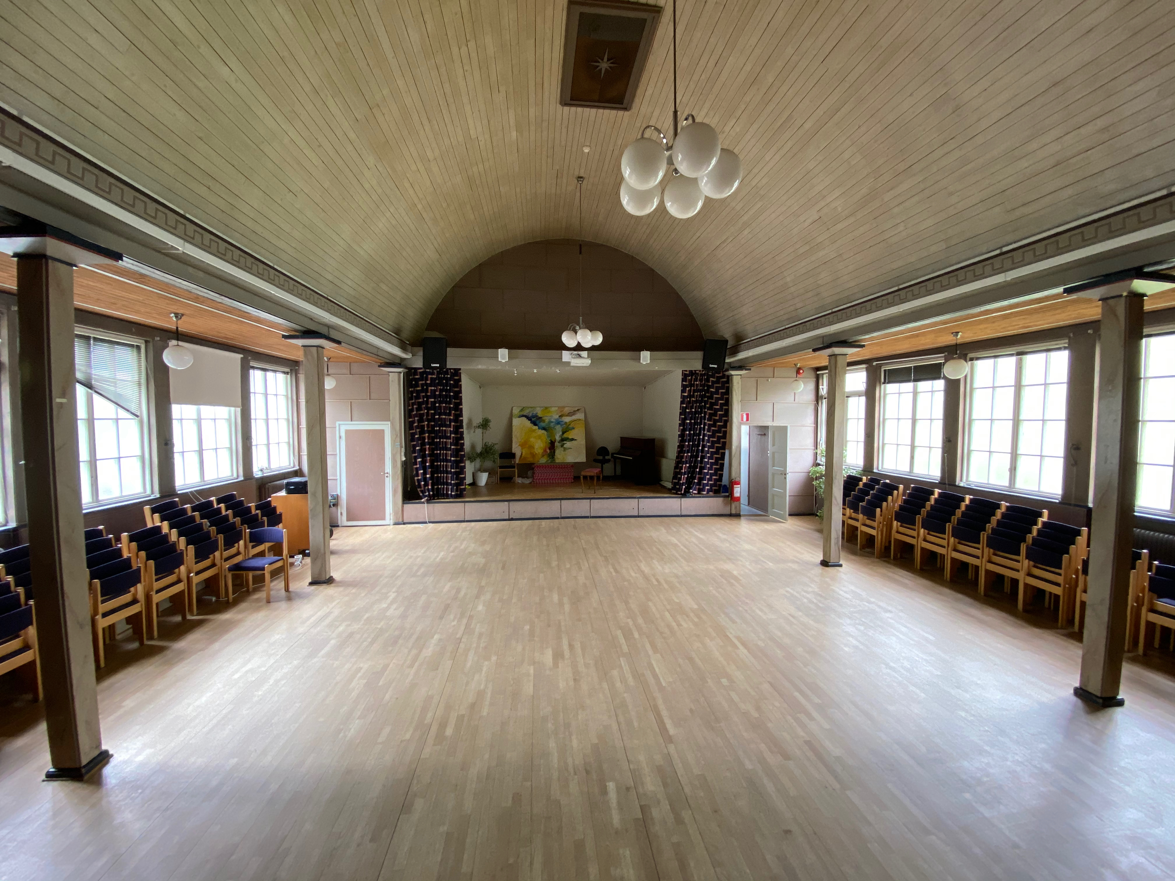 Salen med scen och tavla, stolar på sidorna