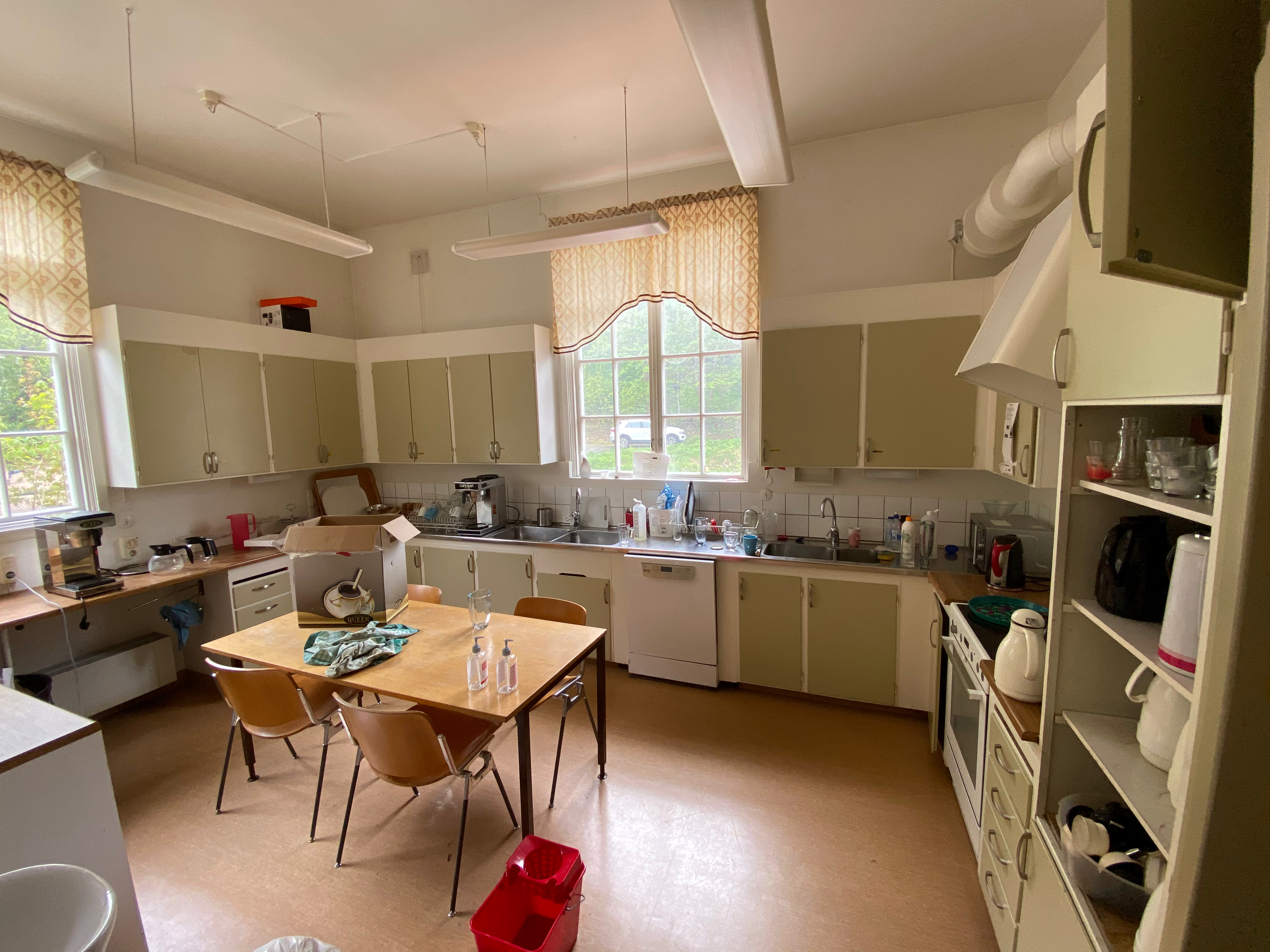 Gammalt kök med gröna skåp och daterade vitvaror