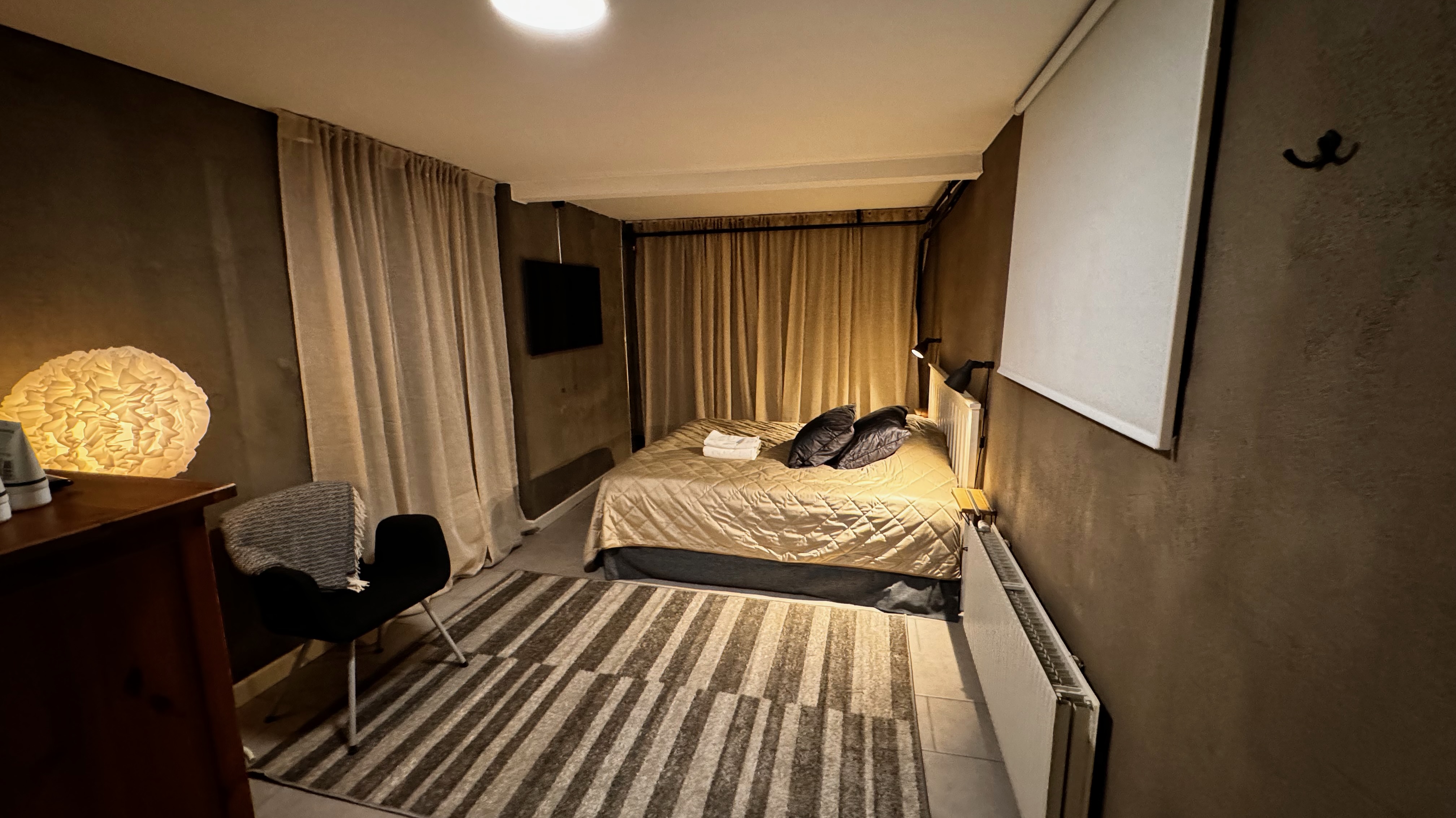 Gästrum i källaren med säng, skrivbord och matta