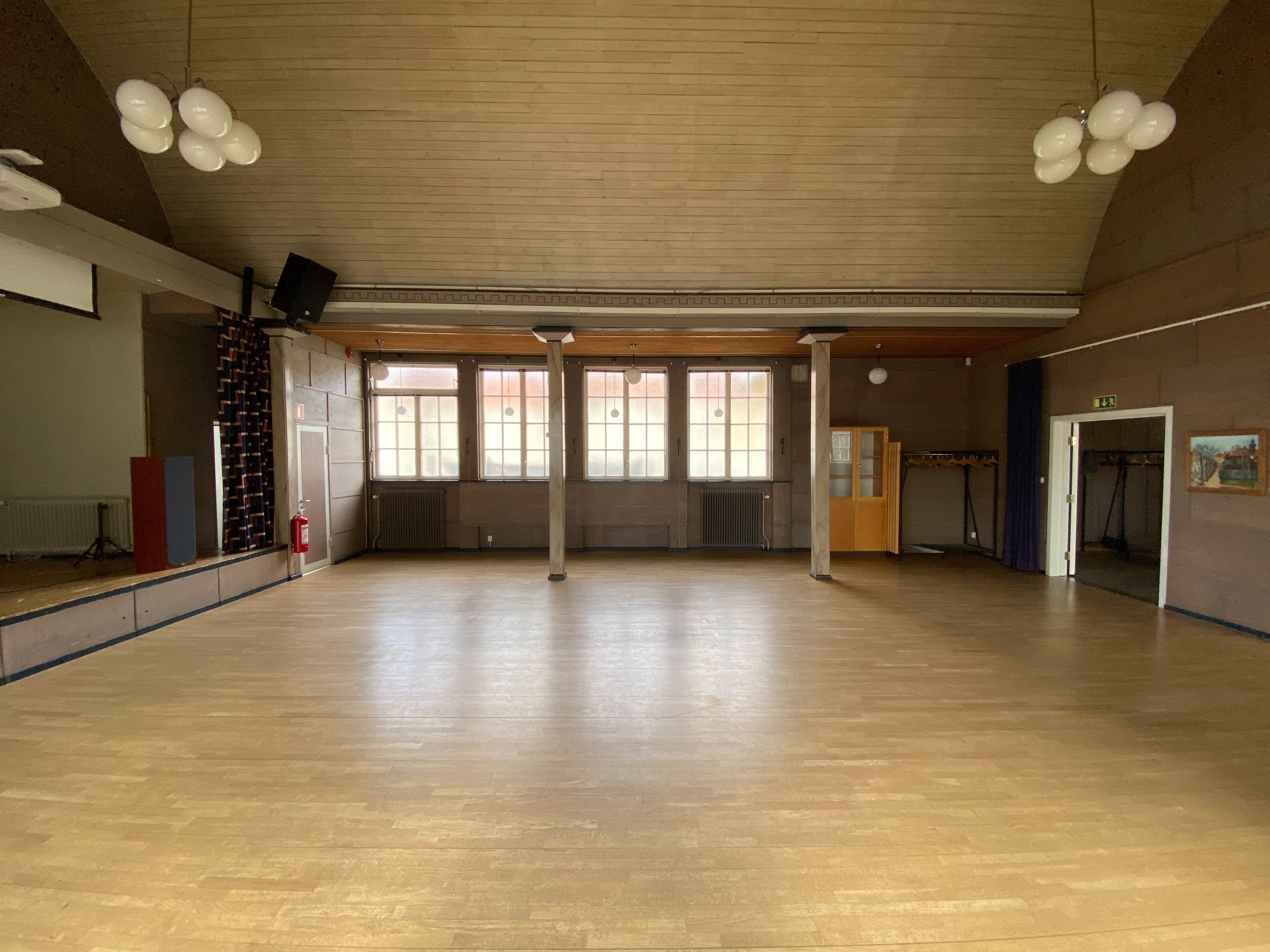 Salen med scen, högtalare och projektorduk efter städning