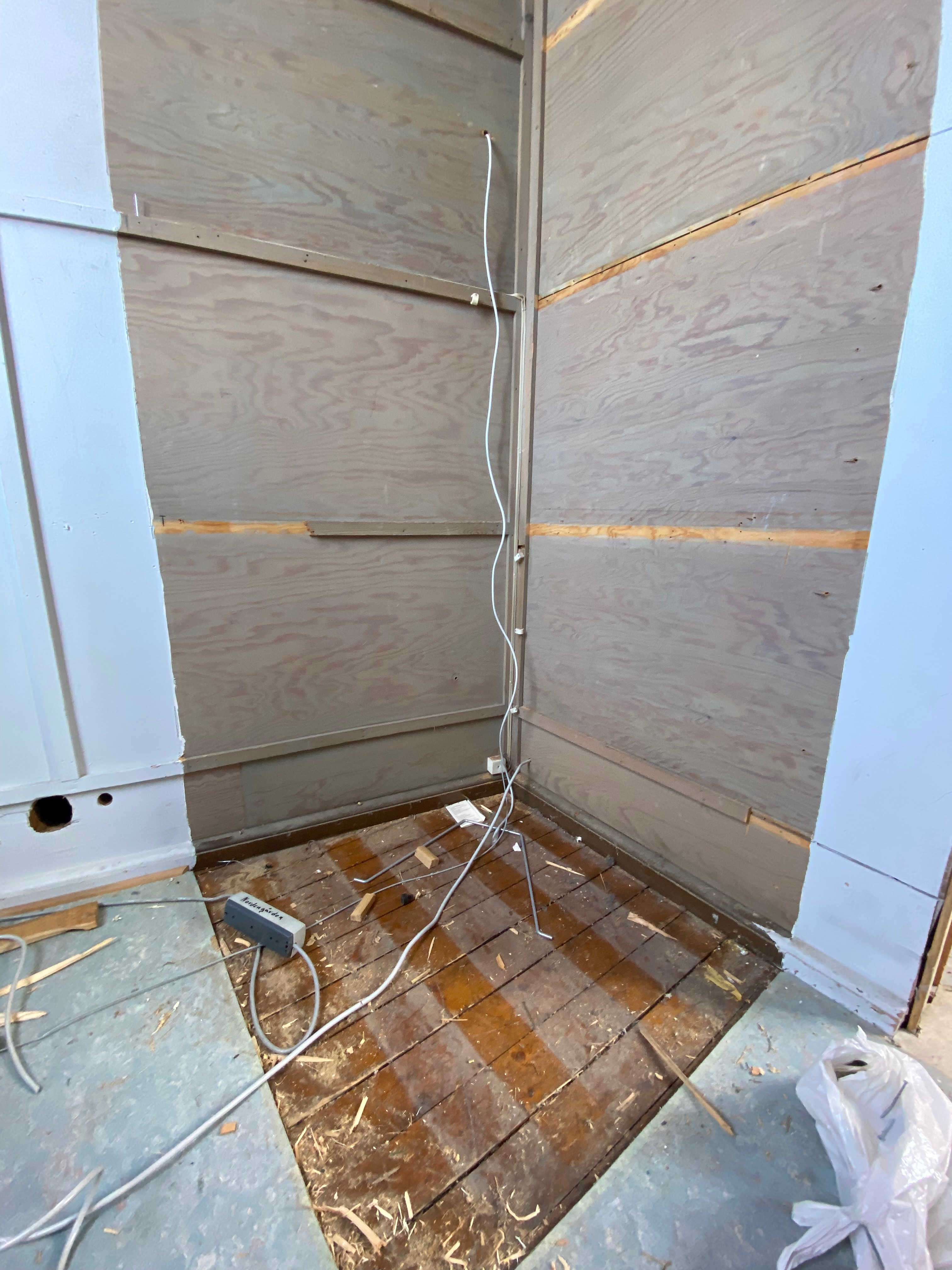 Plywoodskivor på väggar och hängande kablar